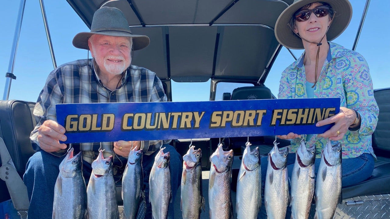 Two anglers on Capt. Monte Smith's boat holding a Gold Country Sport Fishing board with ten Don Pedro kokanee
