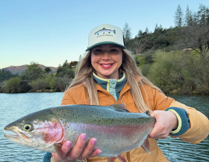 Angler holding a rainbow trout on the water; fishing photo, not a picture of bundle contents