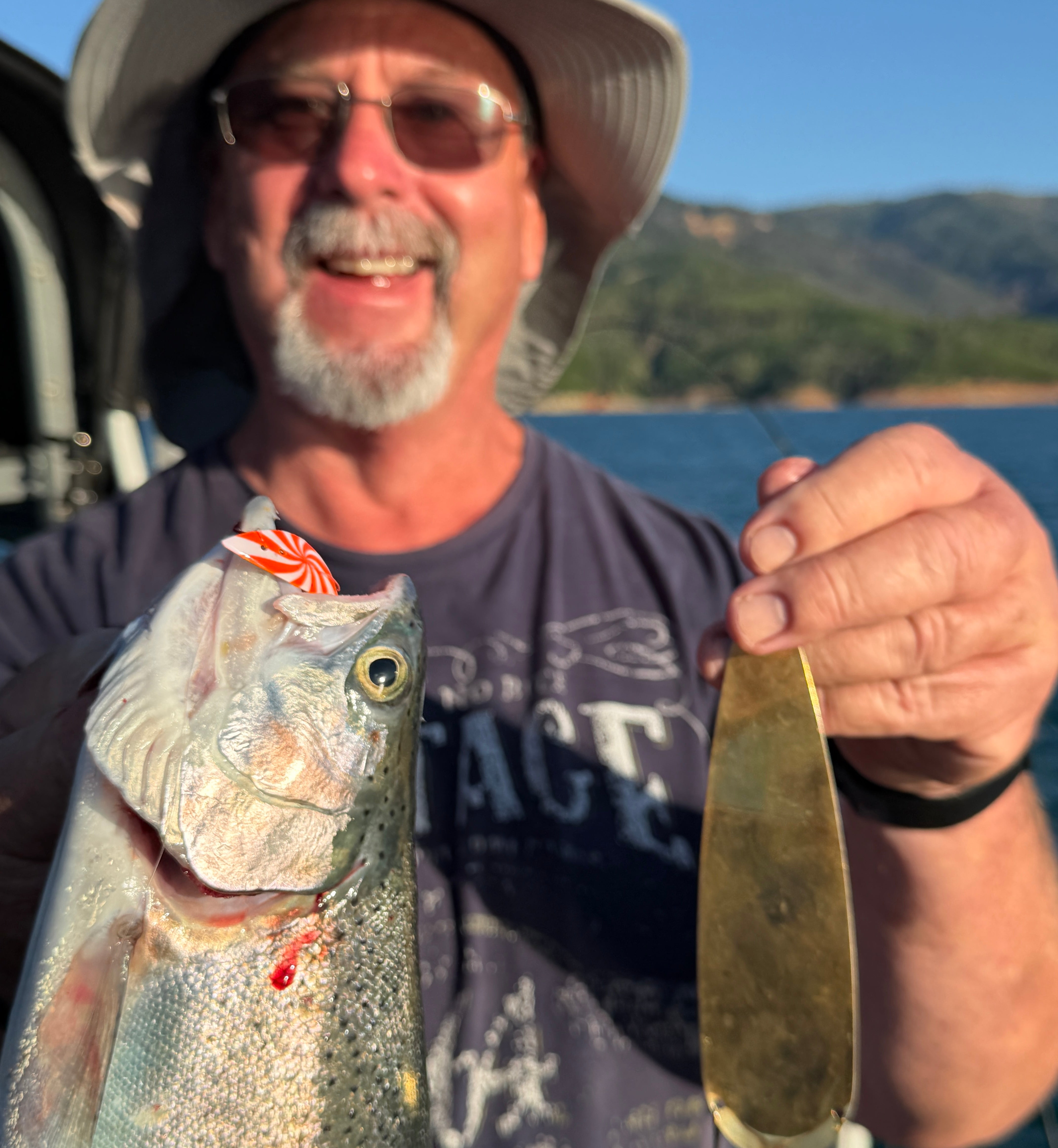 Angler holding a trout caught on X-Pex behind a gold dodger